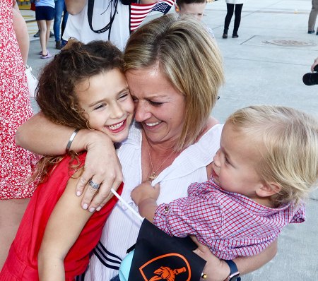 Katie Cochran hugs her children upon seeing her husband's plane.